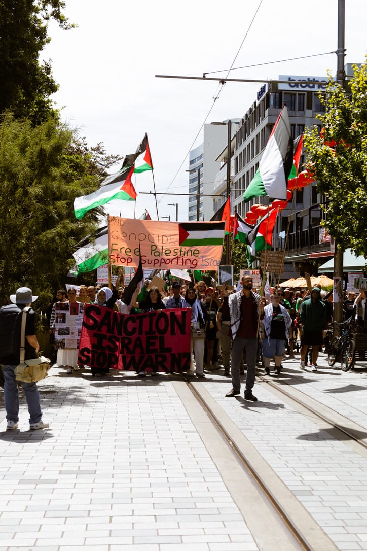 A large crowd marching down Christchurch's Cashel mall in support of Palestine, holding banners and Palestinian flags